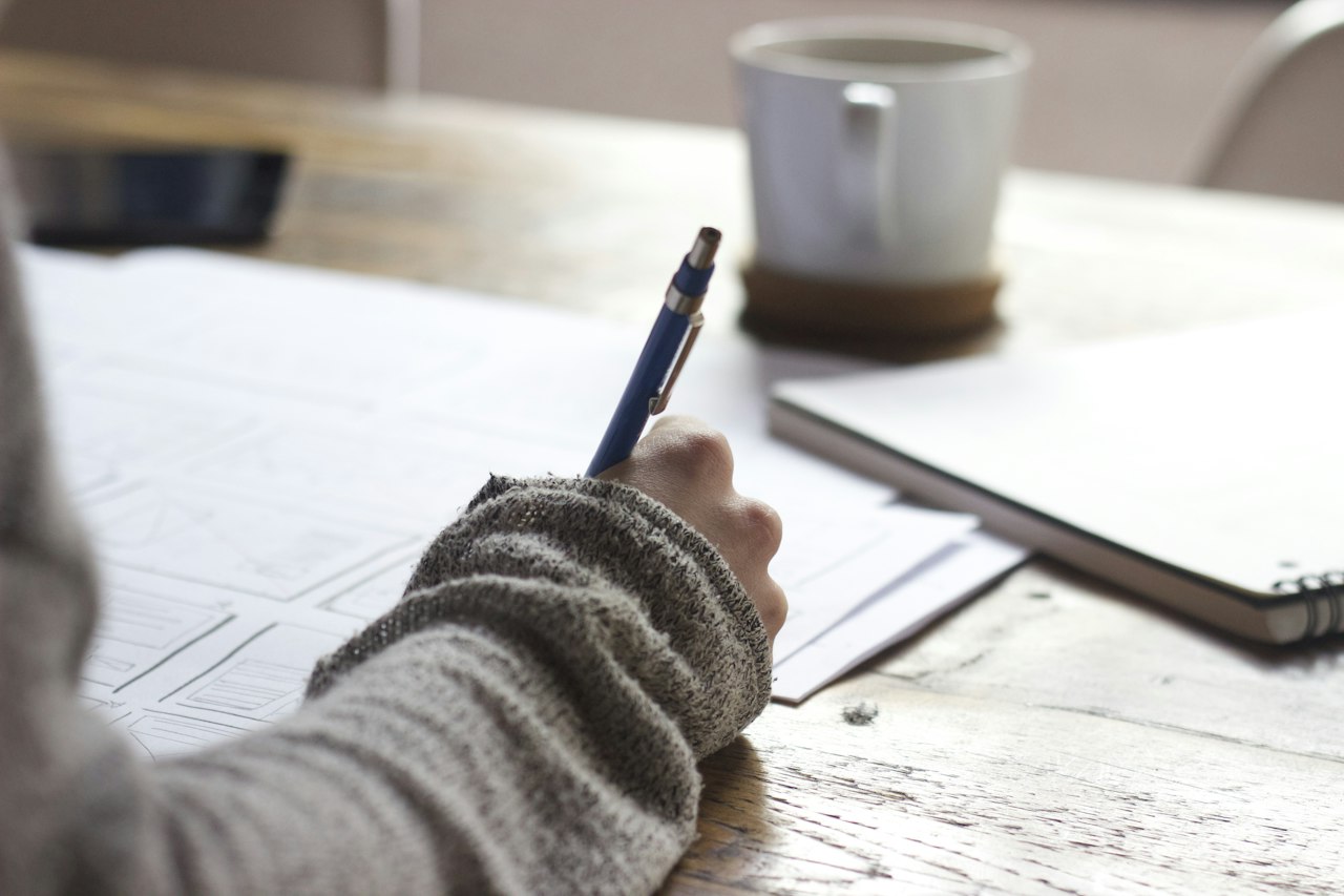 Hand writing goals in a notebook during a planning session